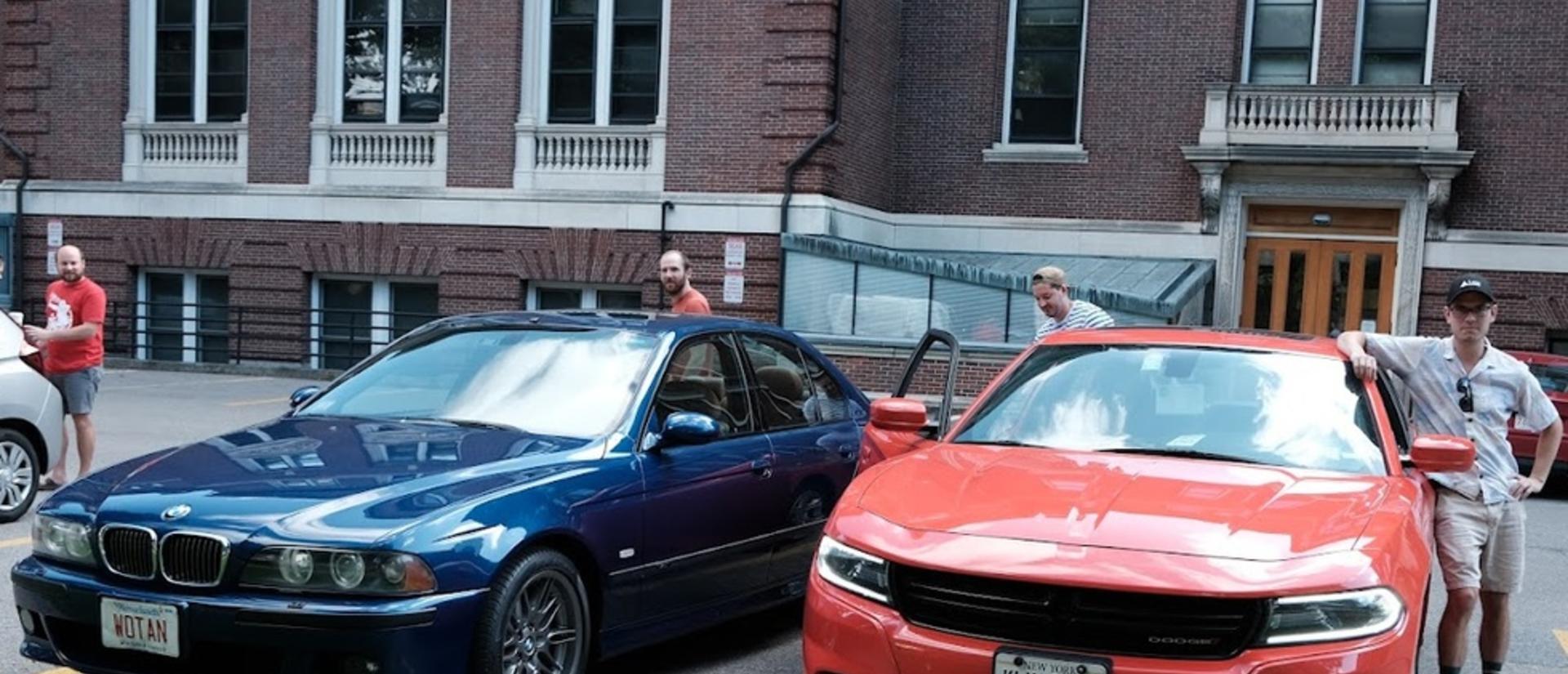 Group members stand besides two cars, a blue one on the left and a very fast looking orange one on the right, loading up to head to the retreat!